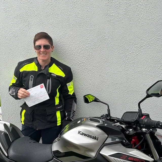 Rider in full gear holding a certificate beside a Kawasaki Z650