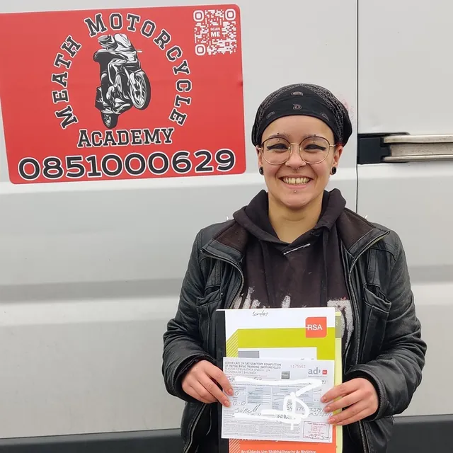 Rider holding their RSA IBT completion certificate beside the academy van