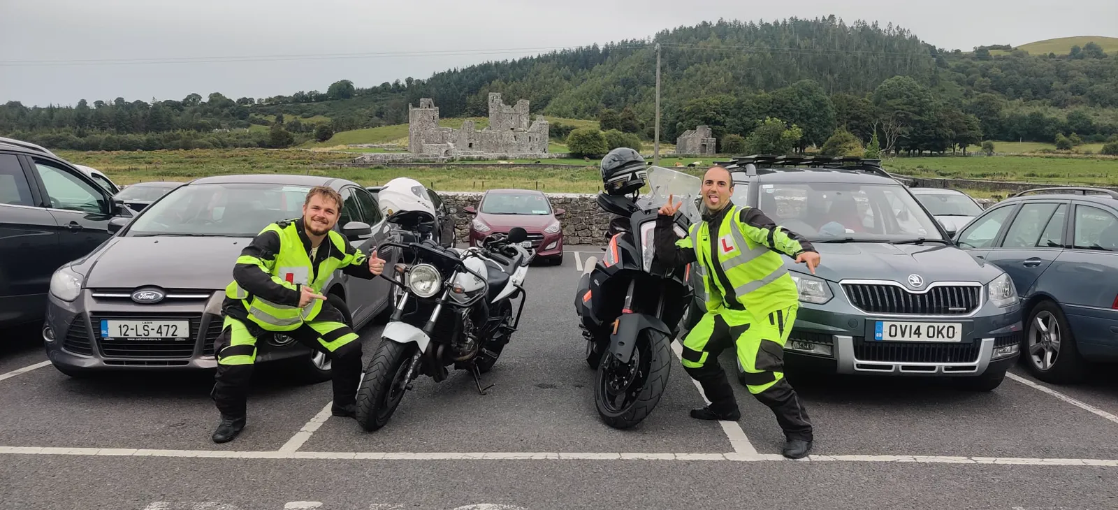 Two Meath Motorcycle Academy students in hi-vis with motorcycles in front of an Irish abbey ruin
